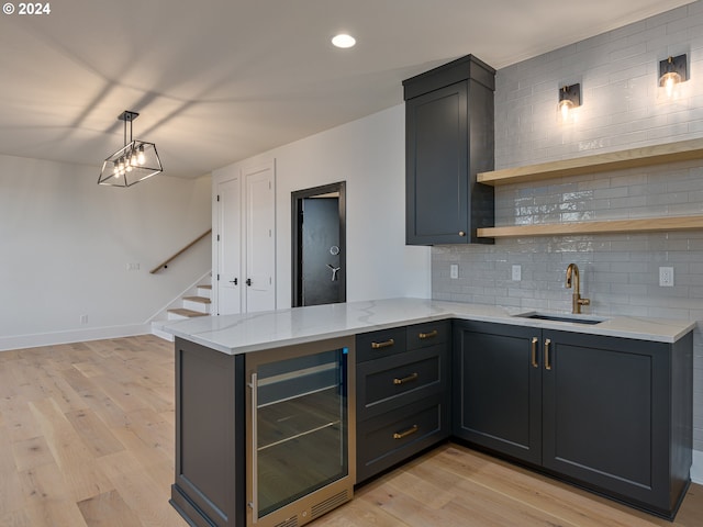 kitchen featuring kitchen peninsula, light hardwood / wood-style floors, wine cooler, and sink