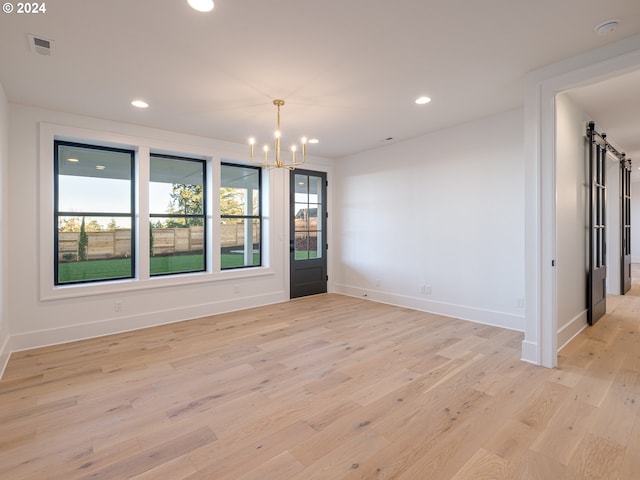 unfurnished room featuring light hardwood / wood-style floors and a chandelier