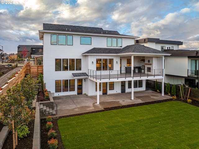 rear view of property with a yard, a patio, and a balcony