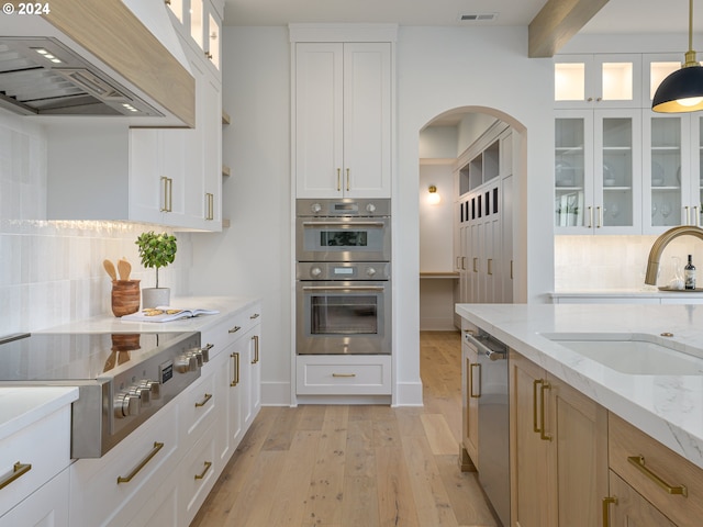 kitchen with light stone countertops, sink, stainless steel appliances, light hardwood / wood-style floors, and custom exhaust hood