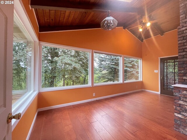 unfurnished sunroom featuring ceiling fan, vaulted ceiling with beams, and wooden ceiling