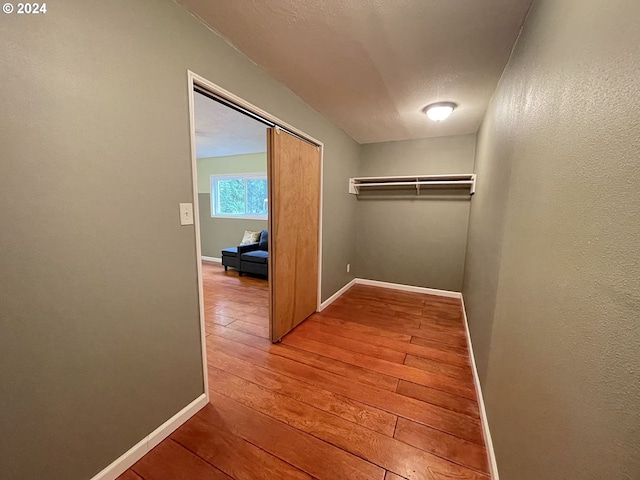 hallway with a textured ceiling and hardwood / wood-style floors