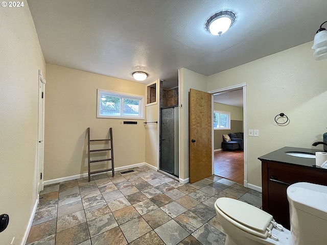 bathroom featuring vanity, a textured ceiling, an enclosed shower, and toilet