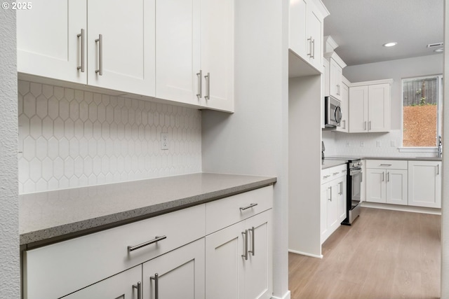 1643 NE Josephine Ct Unit 175, Estacada, OR 97023 - kitchen with stainless steel appliances, light wood-style flooring, tasteful backsplash, white cabinetry, and light stone countertops