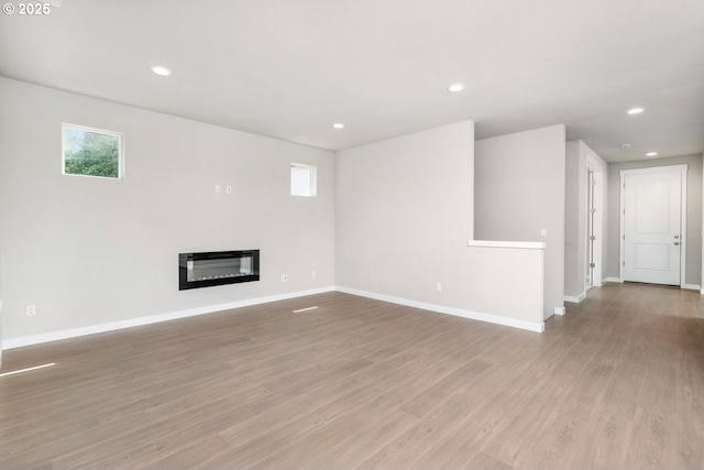 1643 NE Josephine Ct Unit 175, Estacada, OR 97023 - unfurnished living room featuring baseboards, recessed lighting, light wood-style flooring, and a glass covered fireplace