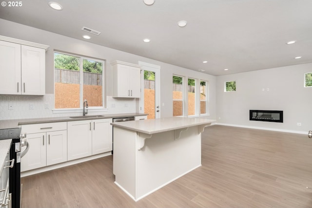 1643 NE Josephine Ct Unit 175, Estacada, OR 97023 - kitchen featuring a sink, electric stove, light wood-style floors, white cabinets, and tasteful backsplash