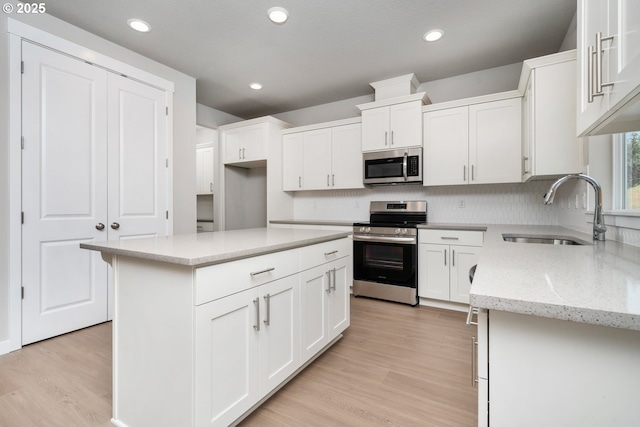 1643 NE Josephine Ct Unit 175, Estacada, OR 97023 - kitchen with appliances with stainless steel finishes, a sink, white cabinetry, backsplash, and light wood-style flooring