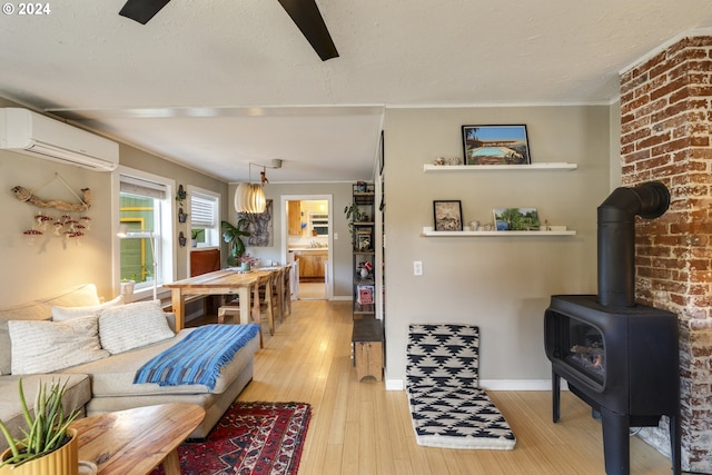 living room featuring a wood stove, light hardwood / wood-style flooring, and a wall mounted AC