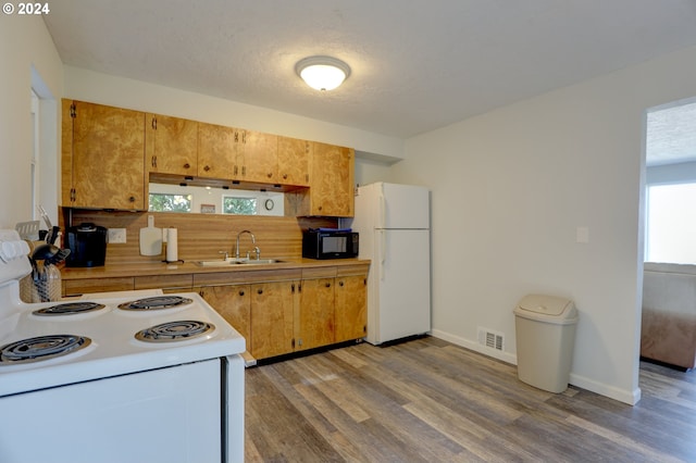 kitchen with hardwood / wood-style flooring, a textured ceiling, sink, and white appliances