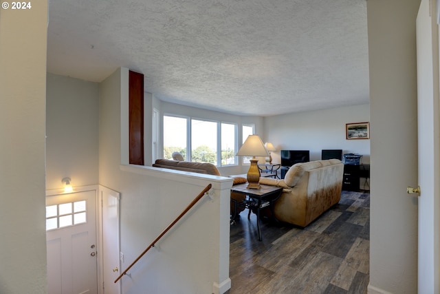 living room with a textured ceiling and dark hardwood / wood-style floors