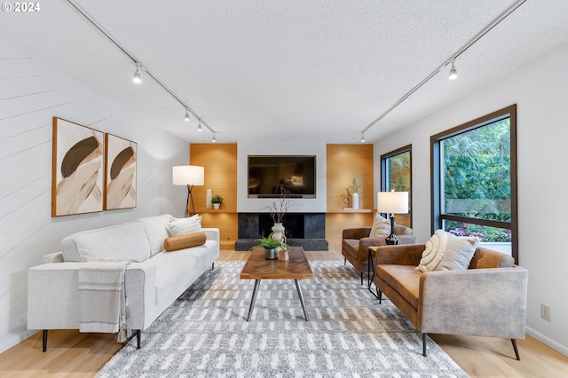 living room with light wood-type flooring, rail lighting, and a textured ceiling