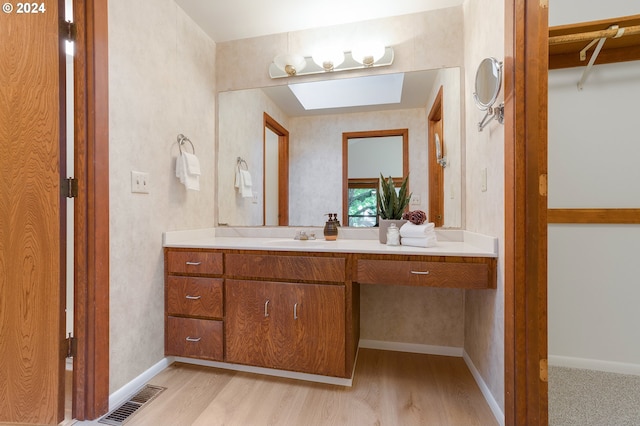 bathroom with vanity, hardwood / wood-style floors, and a skylight