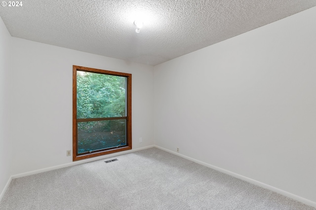 carpeted empty room with a textured ceiling