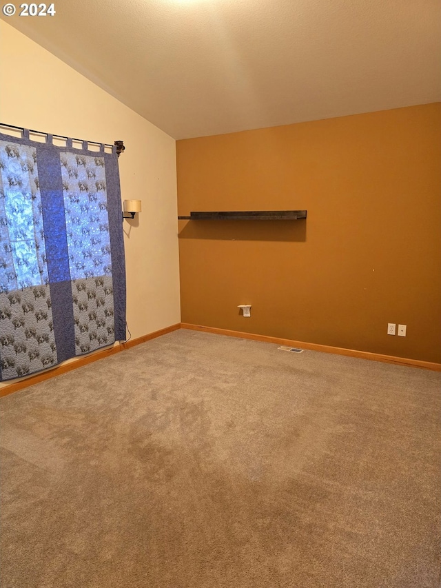 spare room featuring carpet flooring and vaulted ceiling