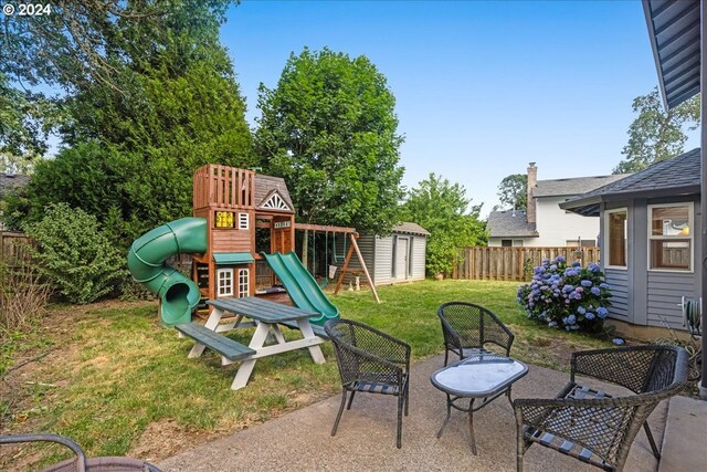 view of play area featuring a patio area, a yard, and a storage shed