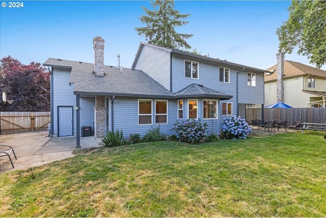 rear view of property with a lawn, cooling unit, and a patio area