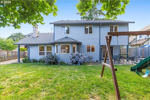 rear view of property with a playground and a yard