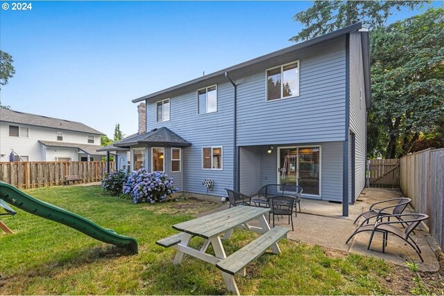 rear view of property with a yard and a playground