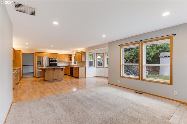 kitchen featuring light carpet, sink, a breakfast bar area, a kitchen island, and stainless steel appliances