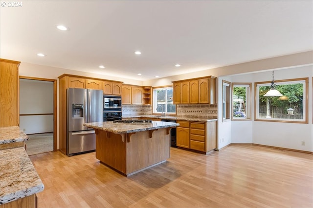 kitchen featuring black appliances, decorative light fixtures, sink, and a wealth of natural light