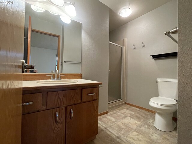 bathroom with vanity, toilet, and a shower with door