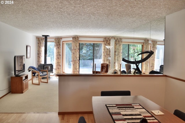 dining space featuring a textured ceiling, a wood stove, and hardwood / wood-style flooring