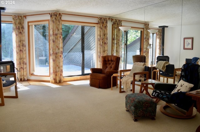 living area with a textured ceiling, a wood stove, and light colored carpet