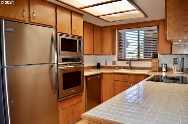 kitchen featuring appliances with stainless steel finishes, sink, and tile countertops