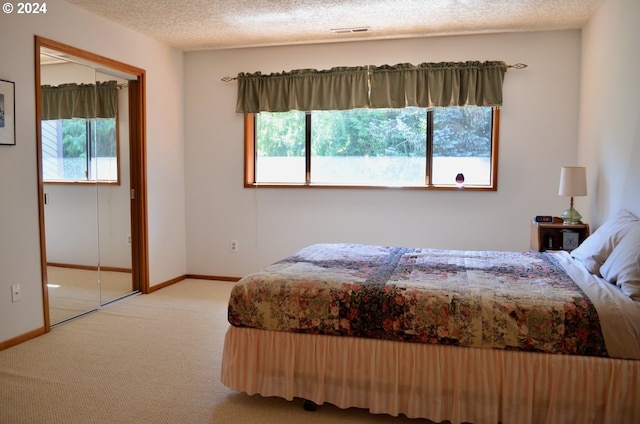 carpeted bedroom with multiple windows, a textured ceiling, and a closet