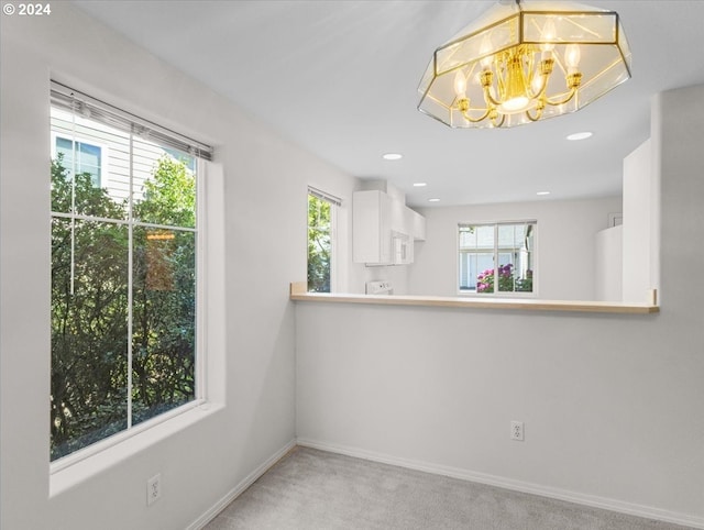 carpeted empty room featuring an inviting chandelier