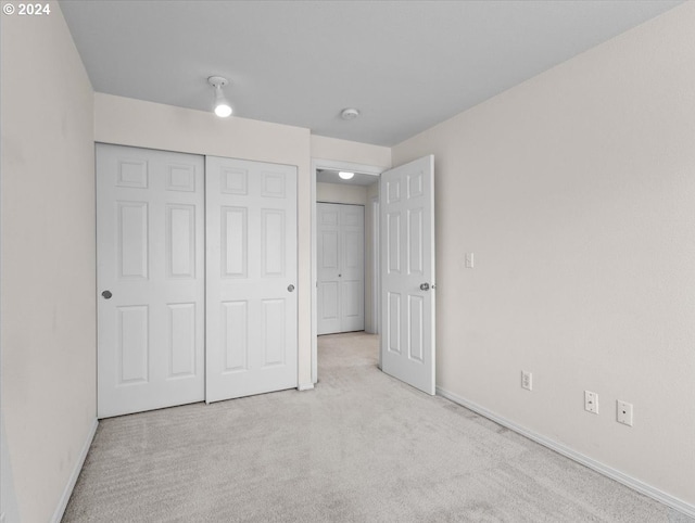 unfurnished bedroom with a closet and light carpet