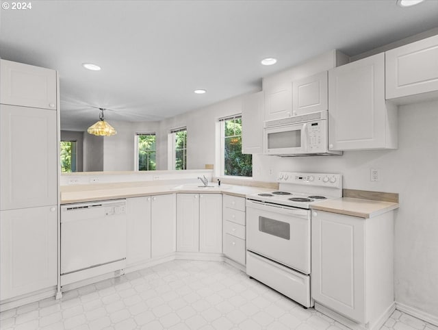 kitchen featuring decorative light fixtures, sink, white cabinetry, a wealth of natural light, and white appliances