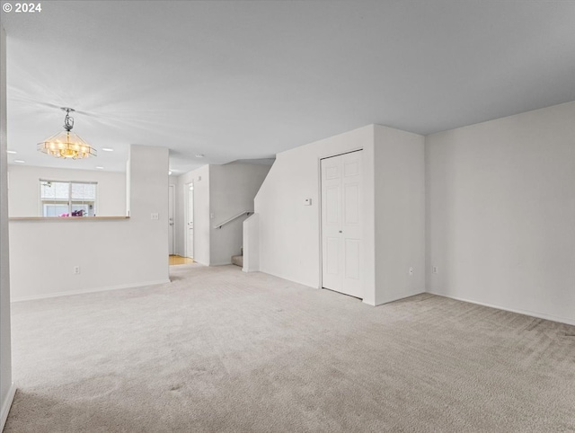 carpeted empty room featuring a notable chandelier