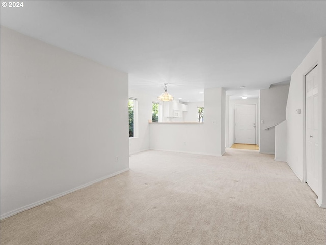 carpeted spare room with a chandelier