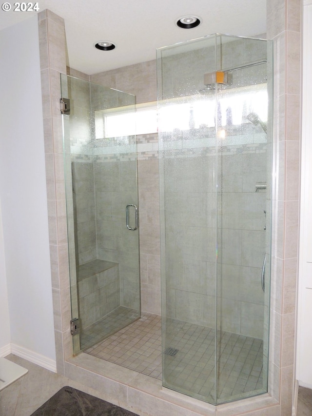 bathroom with an enclosed shower and tile patterned flooring