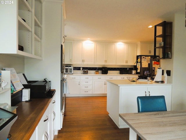 kitchen featuring decorative backsplash, white cabinetry, black fridge, and dark hardwood / wood-style floors