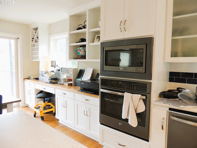 kitchen with appliances with stainless steel finishes, a wealth of natural light, decorative backsplash, and white cabinets