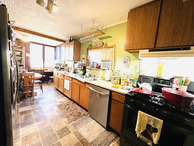 kitchen featuring appliances with stainless steel finishes, a textured ceiling, plenty of natural light, and sink