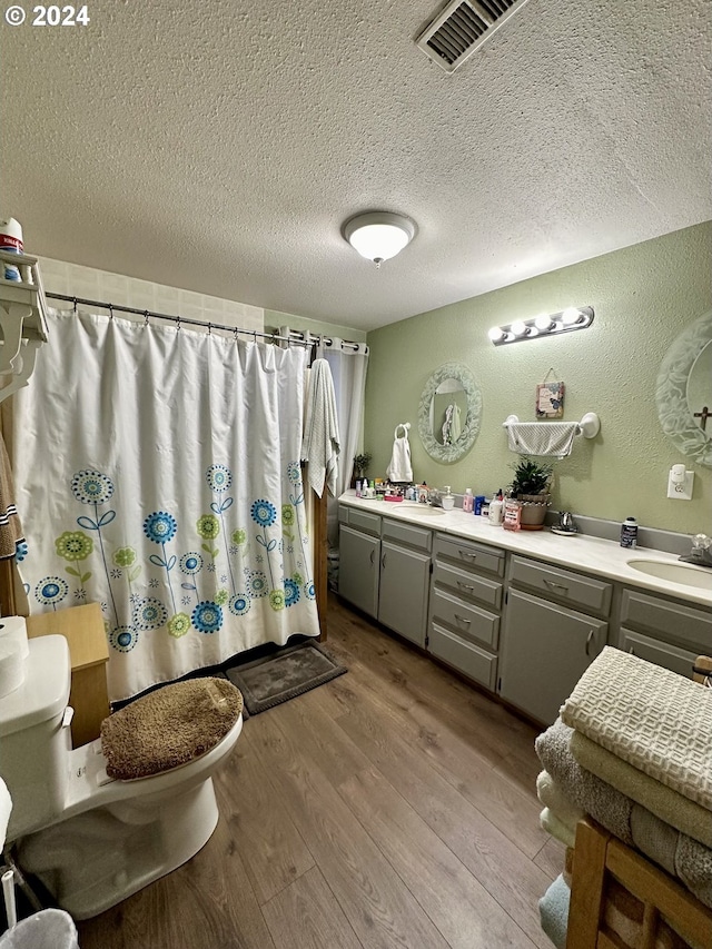 bathroom featuring hardwood / wood-style floors, vanity, a shower with shower curtain, toilet, and a textured ceiling