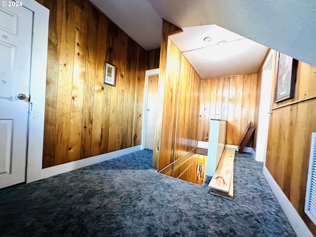 corridor featuring carpet flooring and wood walls