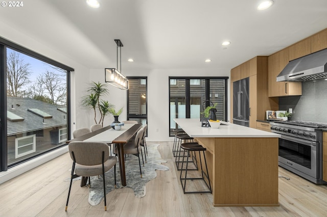 kitchen featuring pendant lighting, a kitchen island, a breakfast bar, light hardwood / wood-style flooring, and high end stainless steel range oven