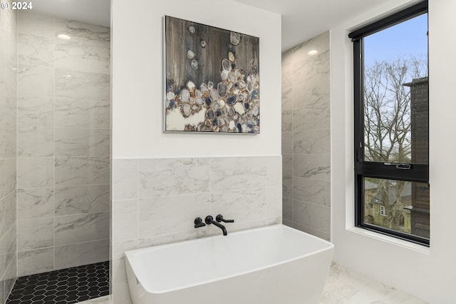 bathroom with tile walls, a tub, tile floors, and a wealth of natural light