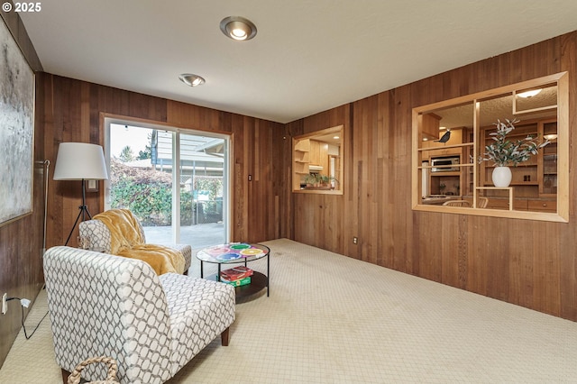 living area featuring carpet flooring and wood walls