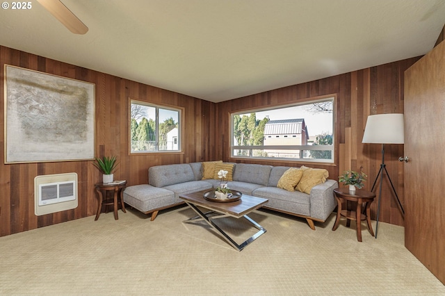 living room with heating unit, wooden walls, and carpet floors