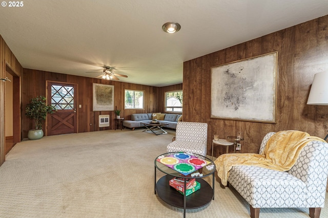 living area with ceiling fan, carpet floors, and wood walls