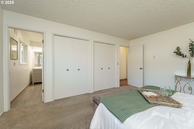 bedroom with light carpet, a textured ceiling, and multiple closets