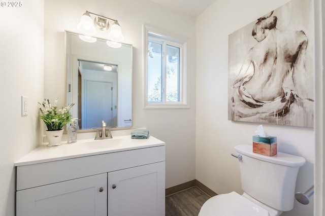 bathroom featuring vanity, toilet, wood finished floors, and baseboards