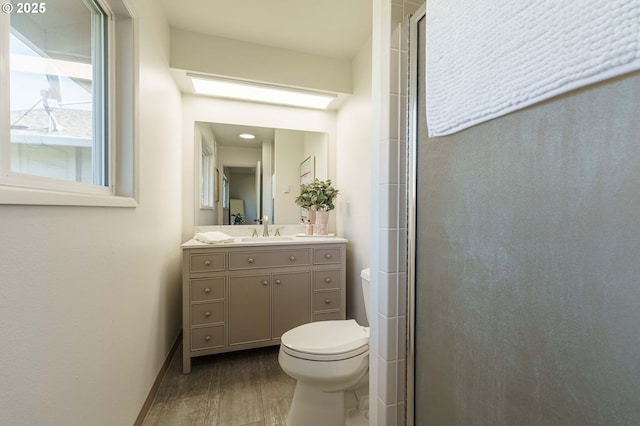 full bathroom with toilet, wood finished floors, a skylight, a shower stall, and vanity