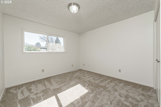 spare room with baseboards, light carpet, and a textured ceiling