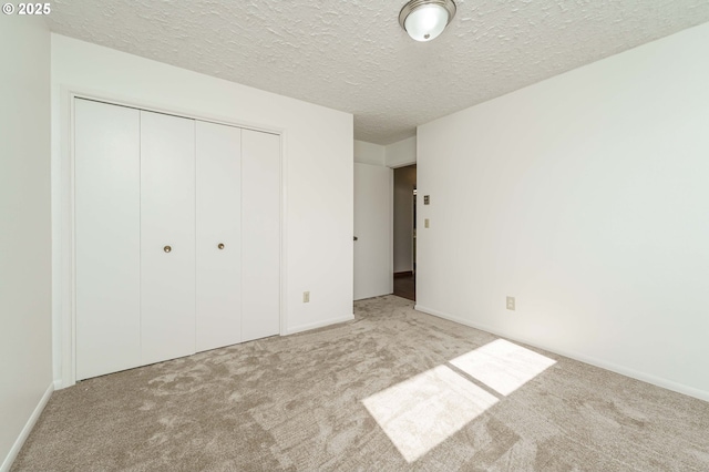 unfurnished bedroom featuring a closet, a textured ceiling, baseboards, and carpet floors